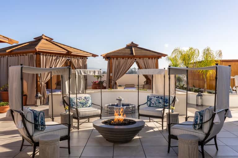 Rooftop lounge with wooden gazebos, fire pit, lounge seating, and scenic city views