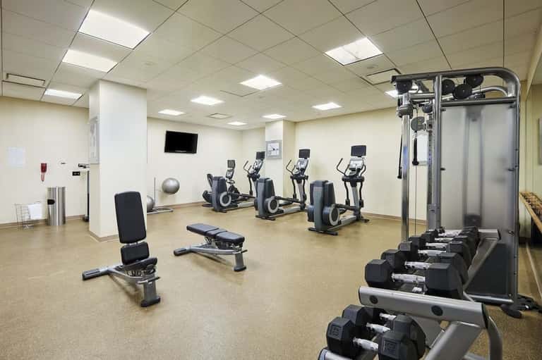 Fitness center with cardio equipment, ellipticals, weight bench, dumbbells, and wall-mounted TV