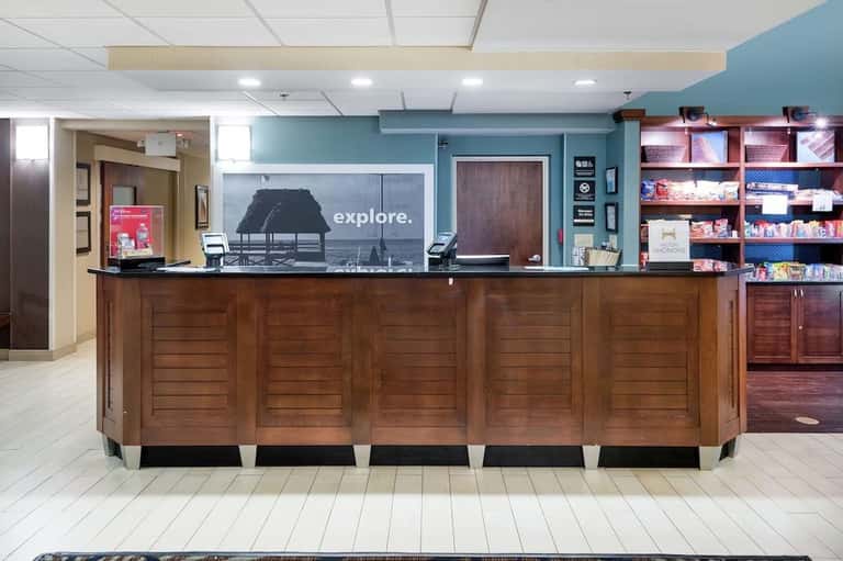 Hotel front desk with wood paneling, reception area, and promotional signage
