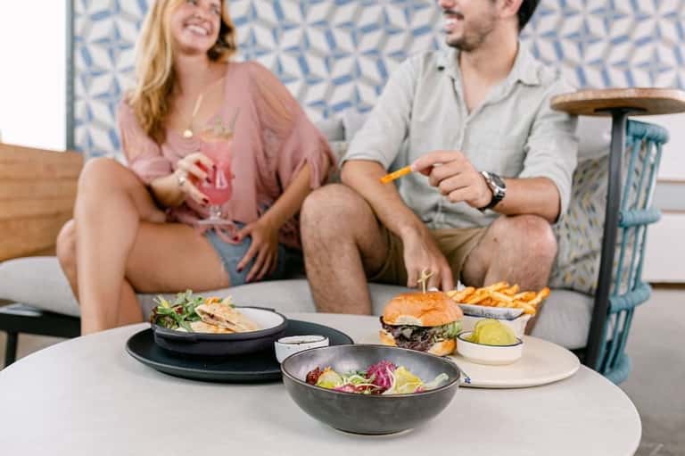 Couple dining poolside with gourmet food and beverages, enjoying casual resort atmosphere