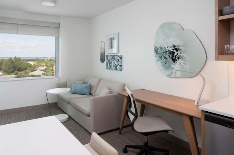 Modern hotel room interior with window view, neutral furnishings, and work desk