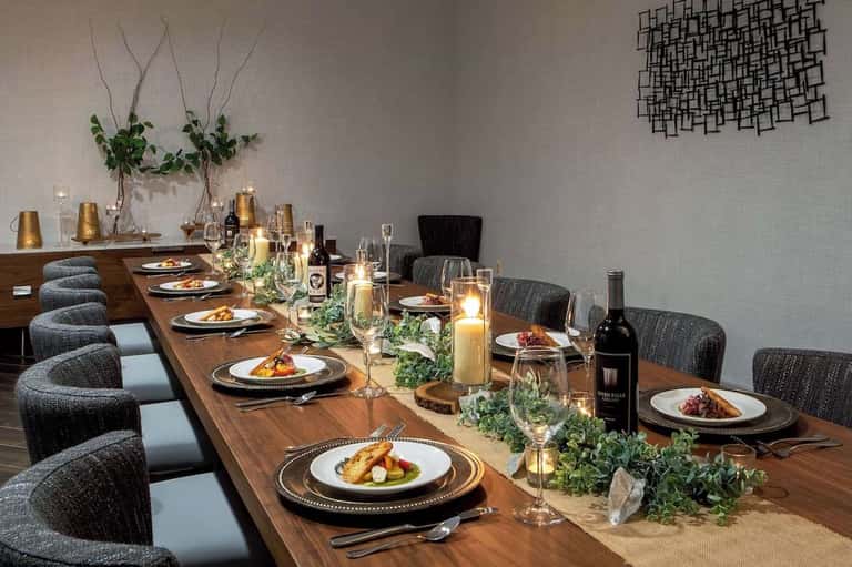 Elegant private dining room with long wooden table, place settings, candles, and floral centerpiece