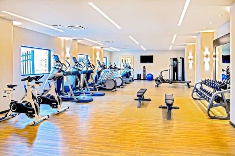 Modern fitness center with cardio machines, ellipticals, dumbbells, and bright lighting
