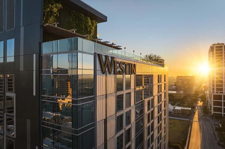 Modern Westin hotel building at sunset with glass façade and city skyline