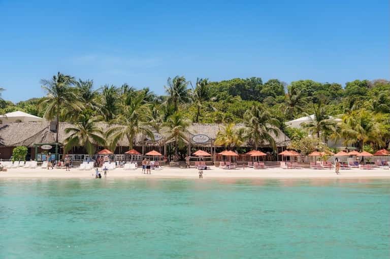 Beachfront resort view showing sandy beach, turquoise water, and palm trees