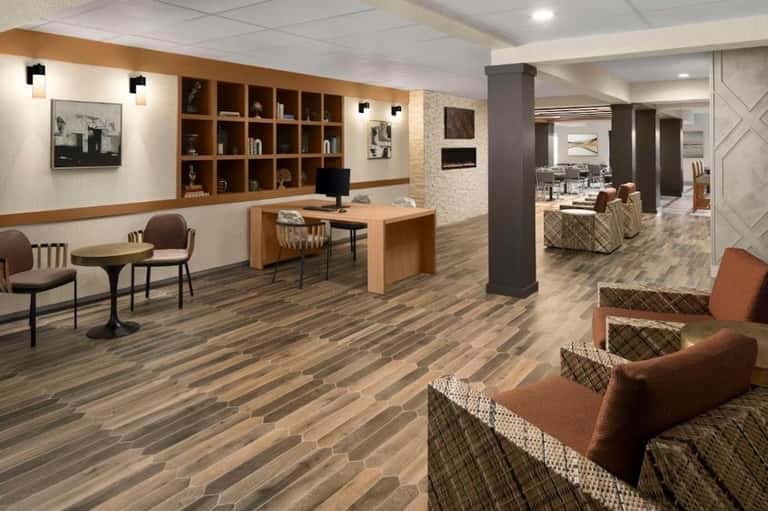 Contemporary hotel lobby with wooden shelving, reception desk, and wood-grain flooring