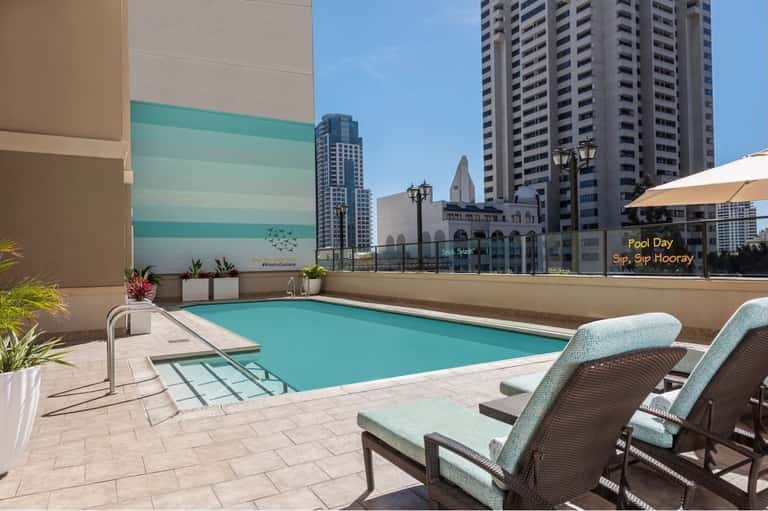 Rooftop pool overlooking city skyline with high-rise buildings and umbrellas