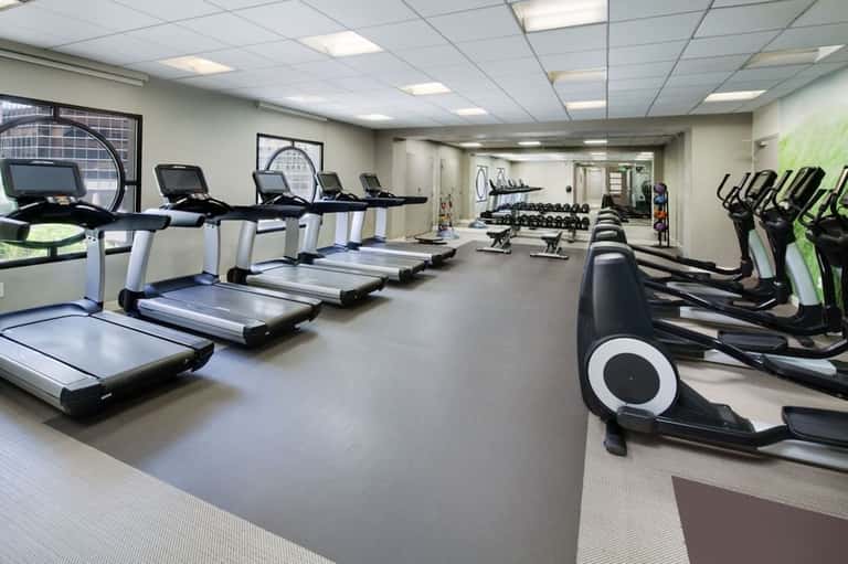 Large fitness room with treadmills, elliptical machines, weights, and exercise equipment
