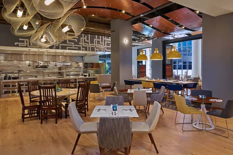 Upscale restaurant interior with open kitchen, gold pendant lights, and contemporary seating