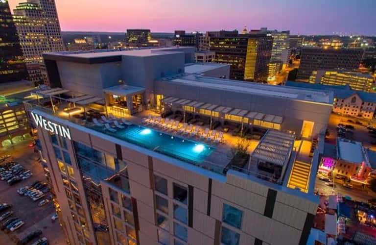 Rooftop pool with blue lighting at The Westin hotel at dusk with city skyline