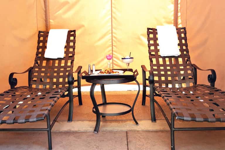 Luxury glamping tent interior with two striped loungers facing a small table with refreshments