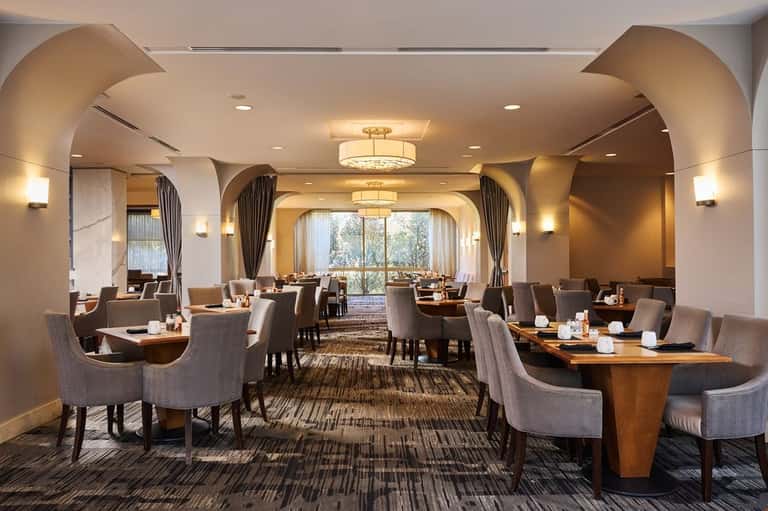 Elegant hotel dining room with arched ceilings, warm lighting, and wooden tables