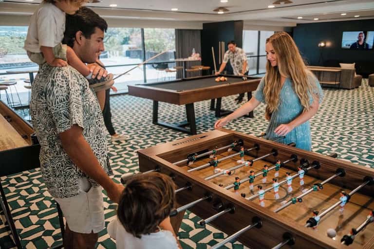 Game room with foosball table, pool table, and guests playing recreational activities