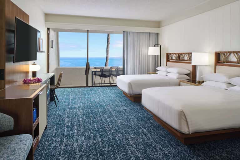Beachfront double queen room with ocean view balcony, modern décor, and TV