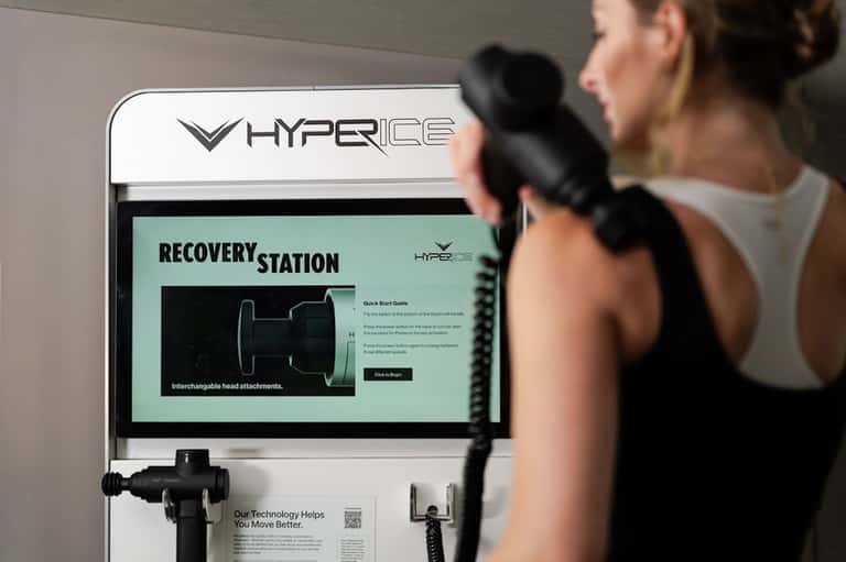 Woman using Hyperice recovery station with massage device in fitness facility