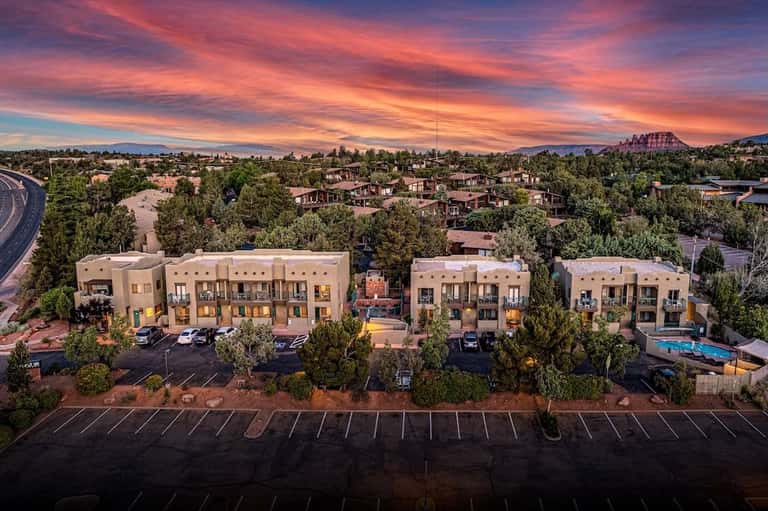 Aerial sunset view of modern tan residential buildings with pool and mountains