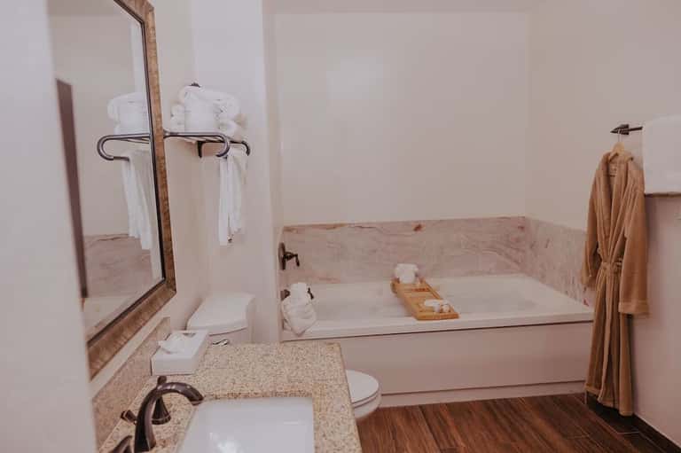 Bathroom with pink marble walls, white sink vanity, and soaking tub