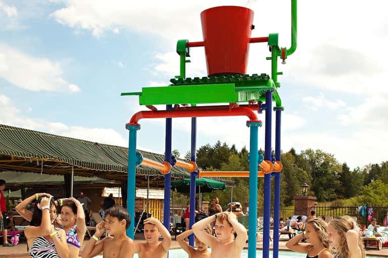 Colorful water dumping bucket playground attraction with children in swimwear underneath