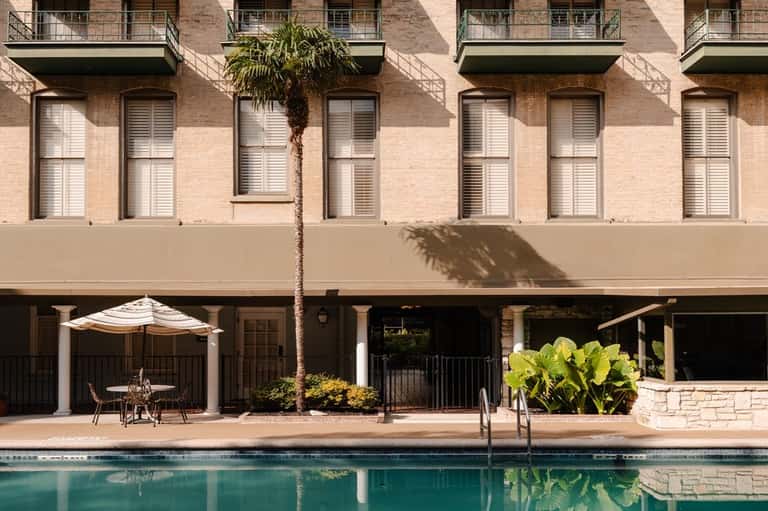 Waterfront hotel pool with brick building facade and ground-level patio seating