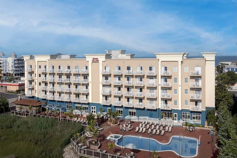 Beachfront resort building with cream facade, blue ground level, and curved pool