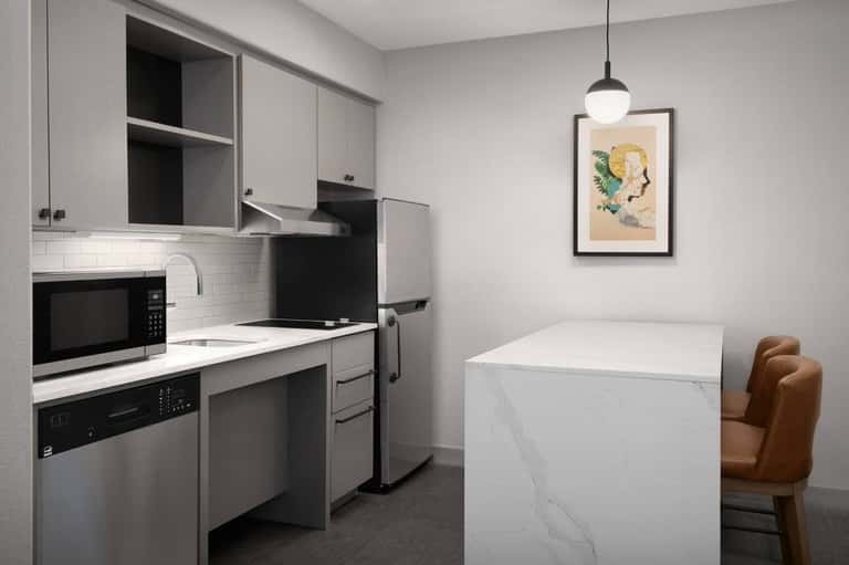 Modern kitchen with white cabinets, stainless steel appliances, and marble island seating