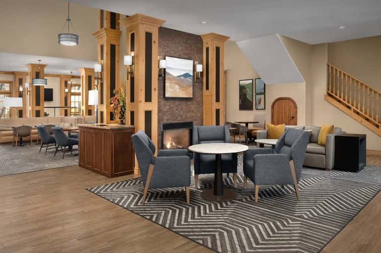 Spacious lobby lounge with fireplace, wooden cabinetry, seating areas, and geometric patterned rug