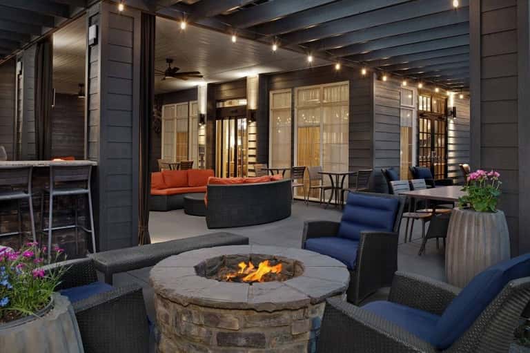 Outdoor patio with firepit, lounge seating, string lights, and access to indoor spaces with large windows