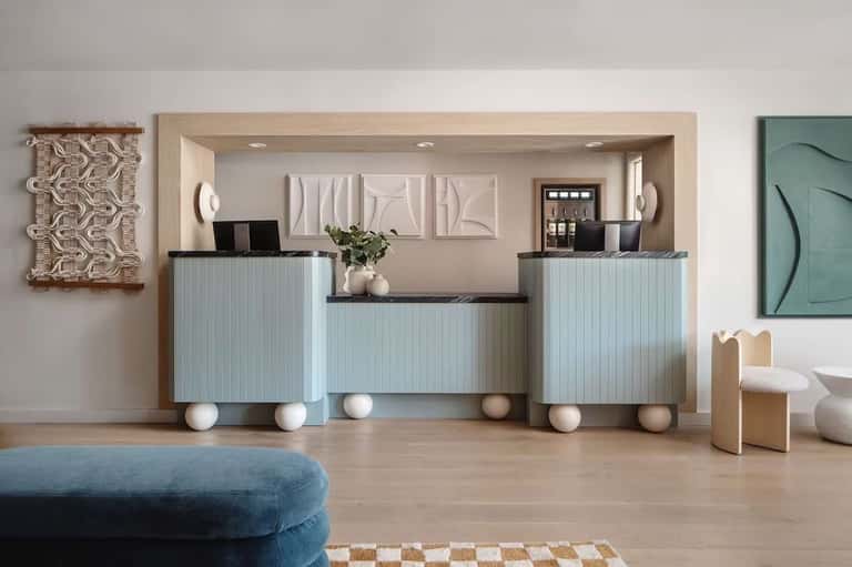 Modern hotel reception desk with light blue paneling, white spherical decorative elements, and contemporary wall art