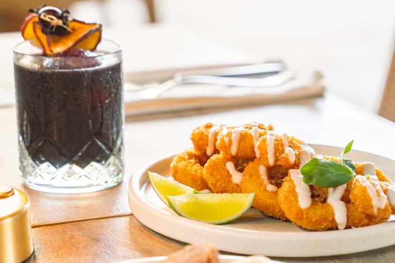 Fried shrimp appetizer with lime and white sauce, served with dark cocktail