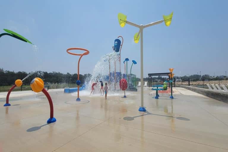 Colorful splash pad with interactive water sprays, arches, and children playing in water features