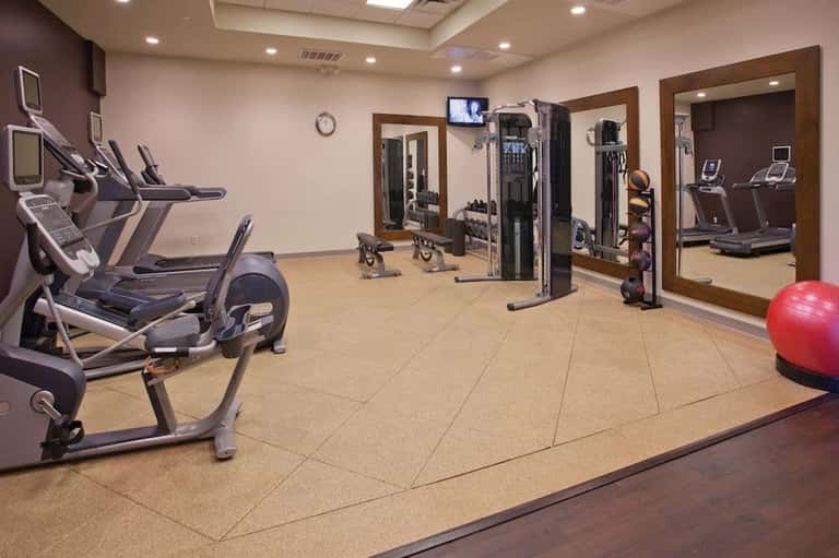 Bright fitness facility with cardio machines, exercise bike, weight equipment, and mirrors