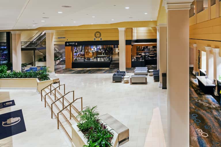 Modern hotel lobby with marble flooring, bar counter, columns, lounge seating, and contemporary architectural elements