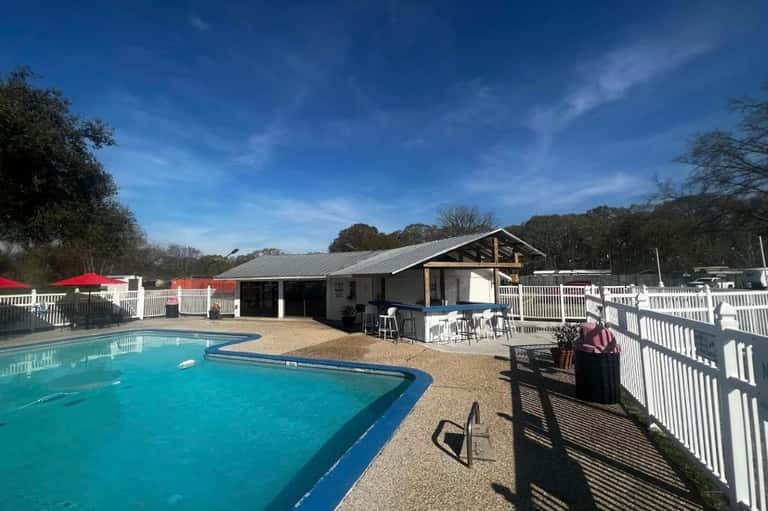 Resort pool facility with blue water, white railing, modern lodge building with pitched roof