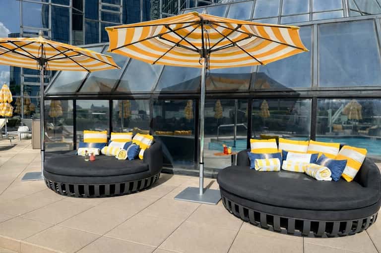 Outdoor pool deck with round sunbeds under yellow-striped umbrellas and contemporary lounge seating