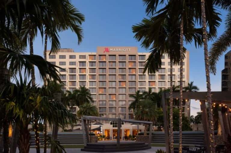 Marriott hotel exterior at dusk with palm trees and illuminated ground-level pavilion