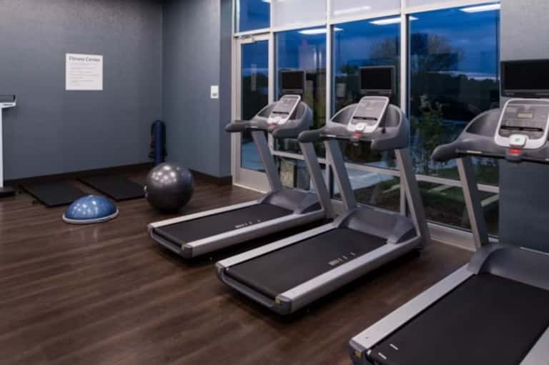 Modern fitness center with treadmills, exercise equipment, wood flooring, and scenic window views
