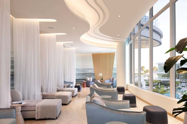 Luxury spa lounge with curved ceiling design, flowing white curtains, and ocean views