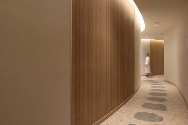 Minimalist hallway with wood-textured curved wall, ambient lighting, and stepping stone floor pattern