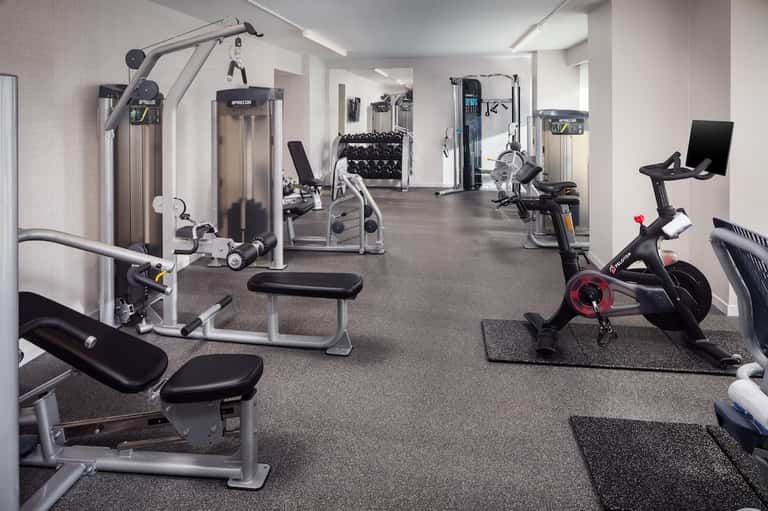 Spacious fitness center with cardio machines, weight equipment, exercise bikes, and dumbbells on gray flooring