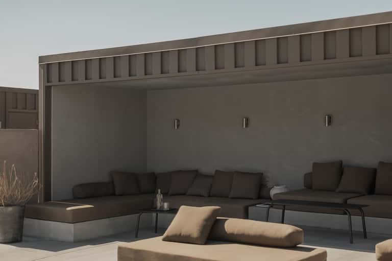 Modern outdoor seating area with dark sofas, beige pillows, and minimalist architectural design