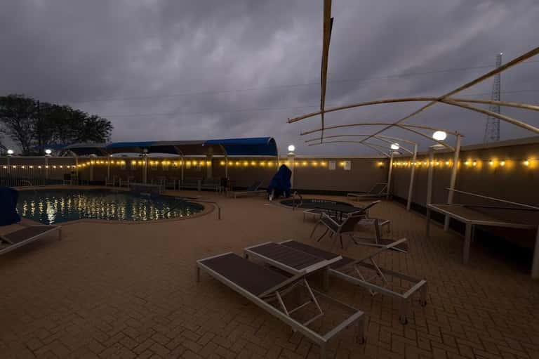 Pool deck with lounge chairs and retractable roof covering at dusk