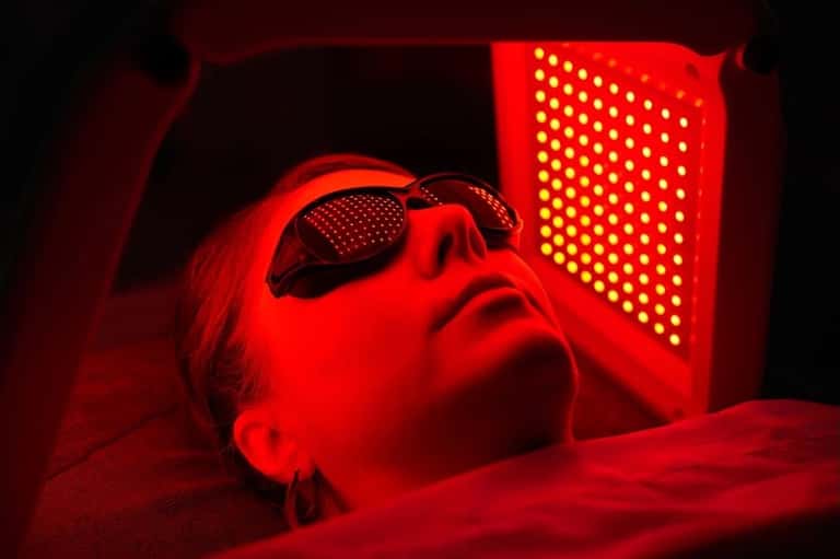 Red light therapy treatment with person wearing protective eyewear under LED light panel