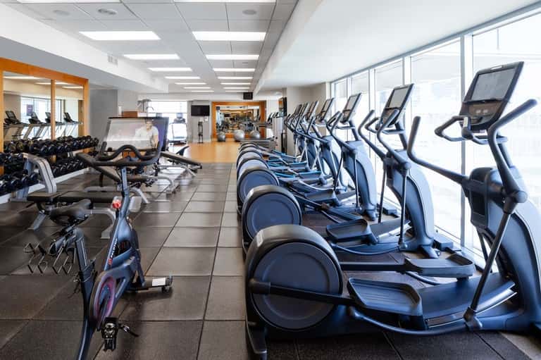 Well-equipped fitness center with cardio machines, exercise bikes, free weights, and large windows