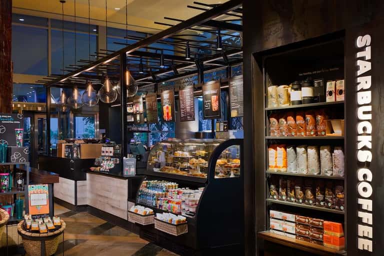 Starbucks coffee shop with black counter, displayed pastries, and shelving with coffee products