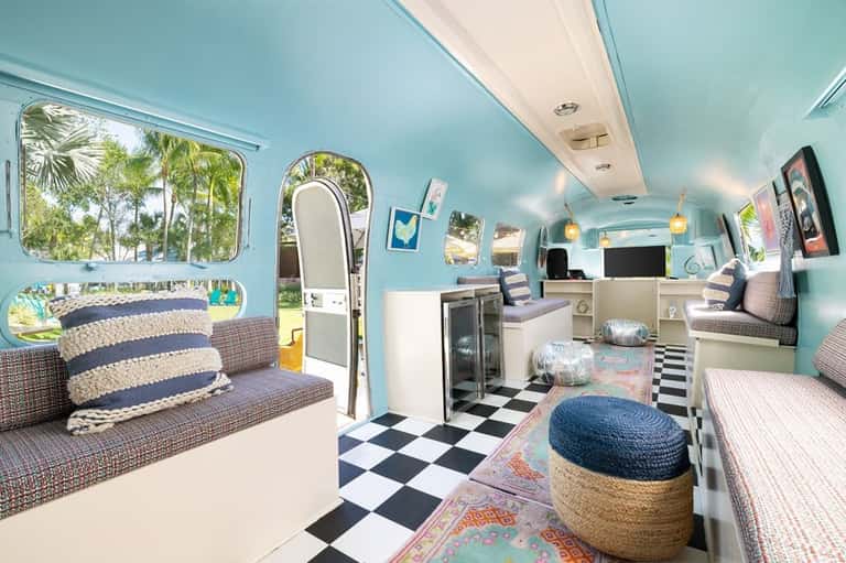 Interior of a vintage-style turquoise Airstream trailer with seating and kitchenette