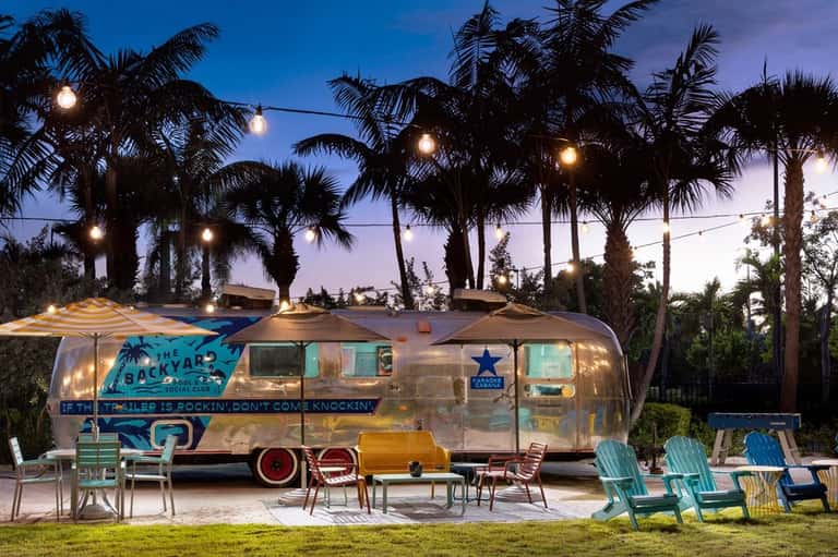 Vintage Airstream trailer bar at dusk with string lights and Adirondack chairs