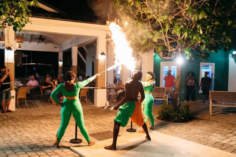 Fire performers entertaining guests at a nighttime poolside event with tropical decorations