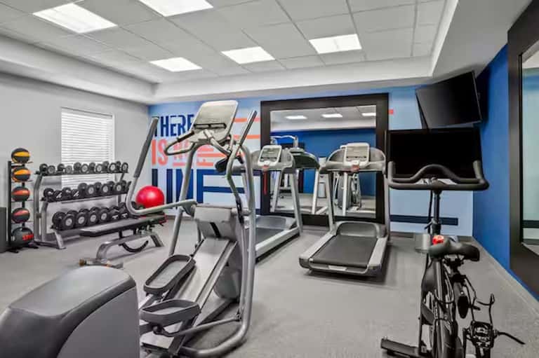 Hotel fitness center with cardio equipment, dumbbells, exercise bike, and motivational wall signage