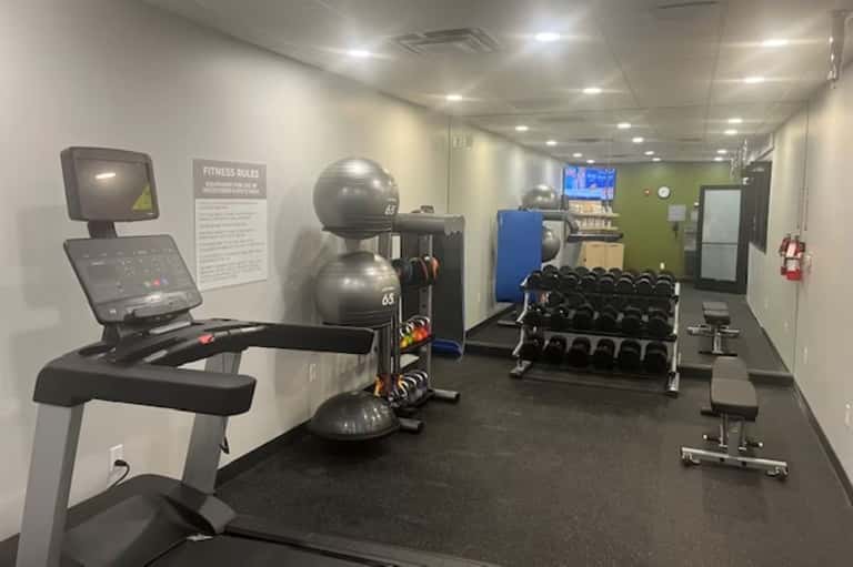 Modern fitness center with exercise bike, stability balls, dumbbell rack, and TV monitor