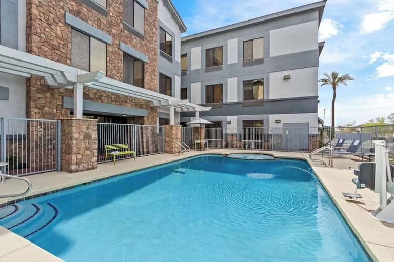 Resort outdoor pool with stone accent wall, lounge chairs, and multi-story hotel building
